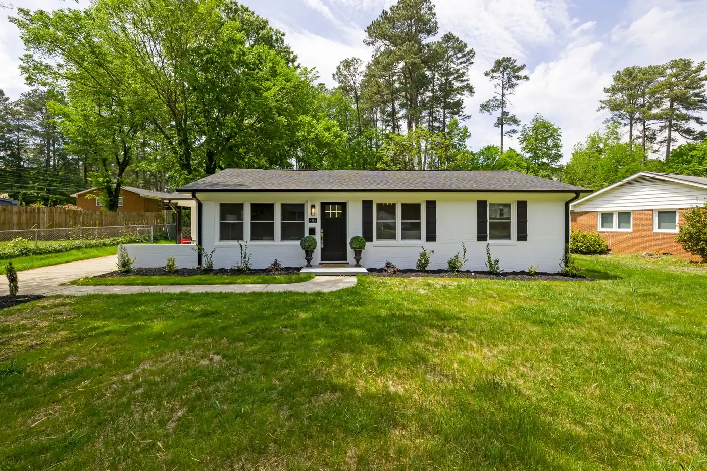 Single-story home with a green front lawn and pine trees